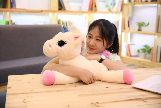 Person holding a unicorn plush toy in a room with shelves and books.