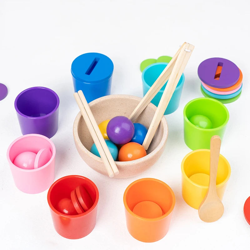 Colorful toy cups with wooden spoons and balls on a white background