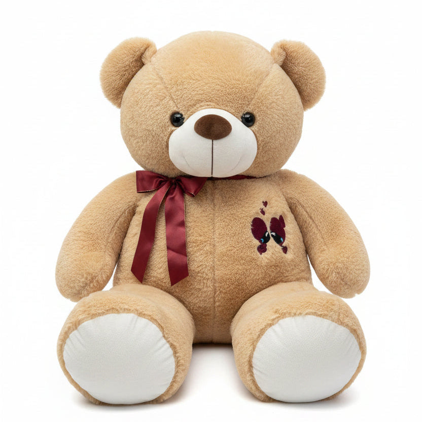 Large beige teddy bear with a red bow and heart design on a chair.
