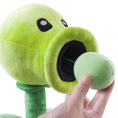 Green plush toy resembling a plant from a video game, held by a hand against a white background 