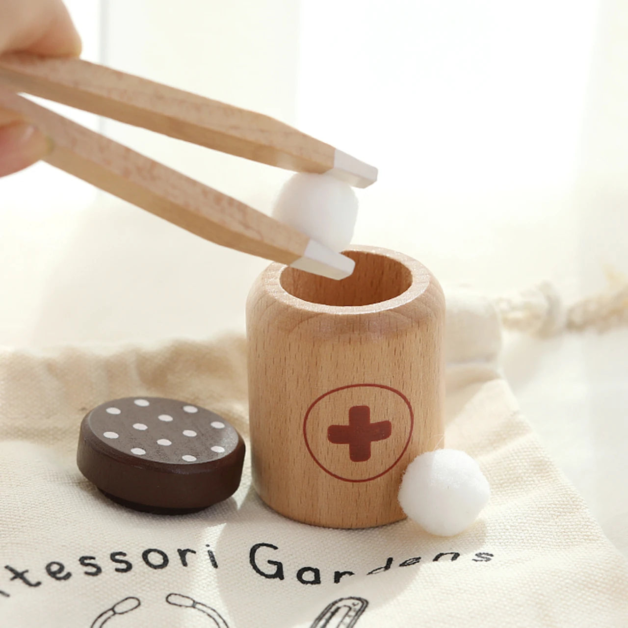Wooden toy with a cylindrical container and round wooden balls, labeled 'Tesssori Gardens'.