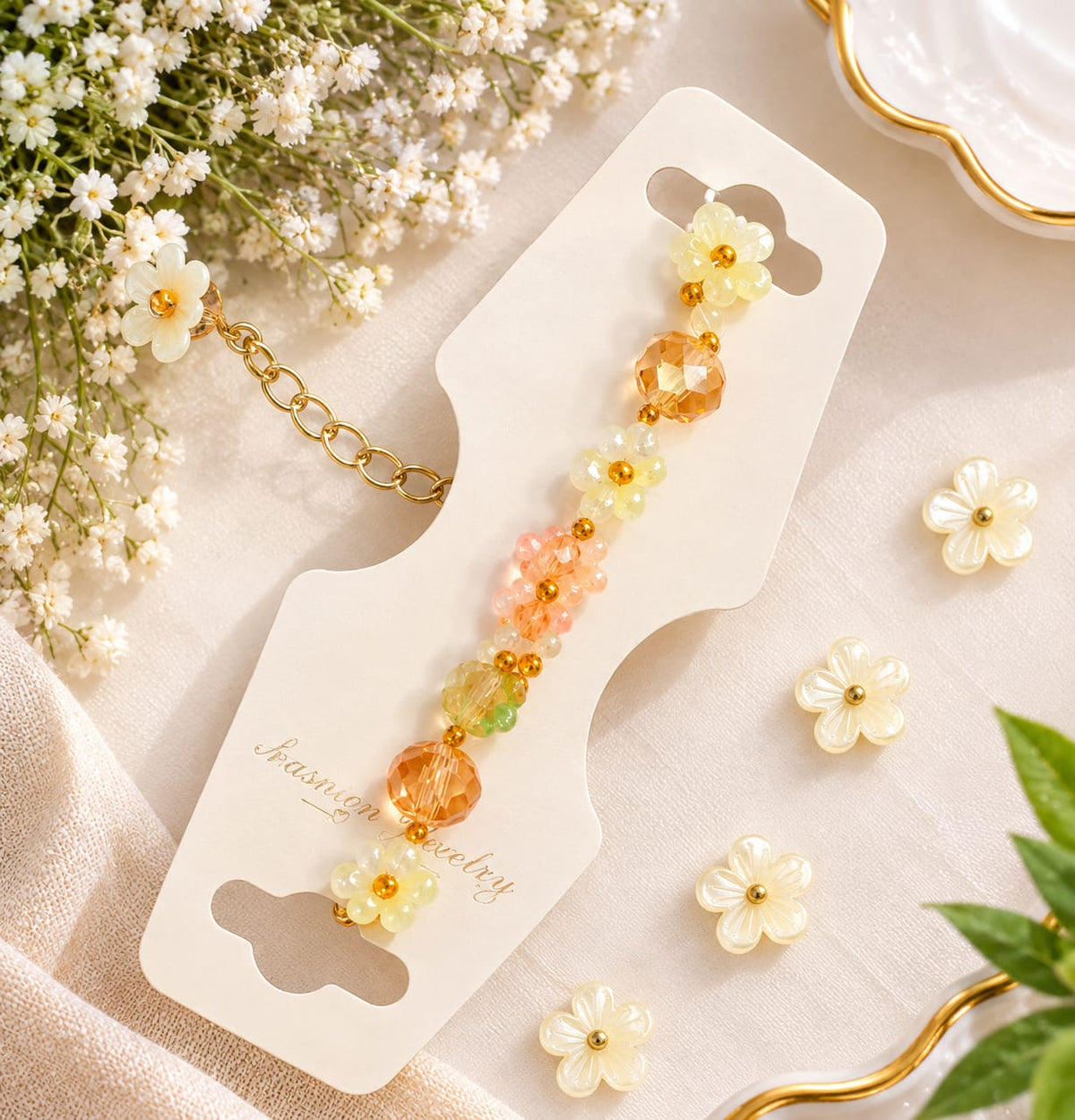 A beaded bracelet with yellow, peach, and white flower charms and gold chain details, displayed on a white card labeled 'Jasmine jewelry' with small white flowers and green leaves around it.