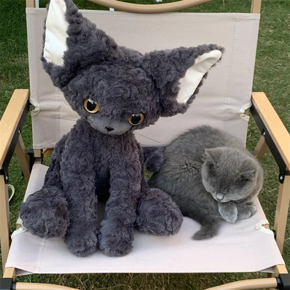 curly devon rex kitten Gray plush toy and real gray cat sitting on a chair outdoors