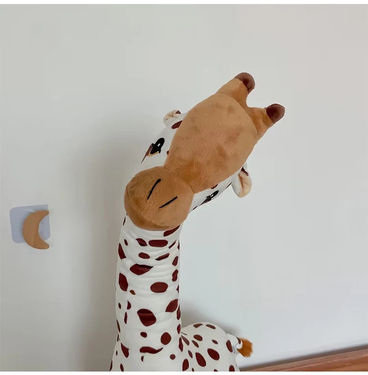 Plush giraffe toy leaning against a light-colored wall.