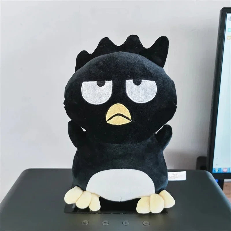 Black plush toy with a sad expression on a desk