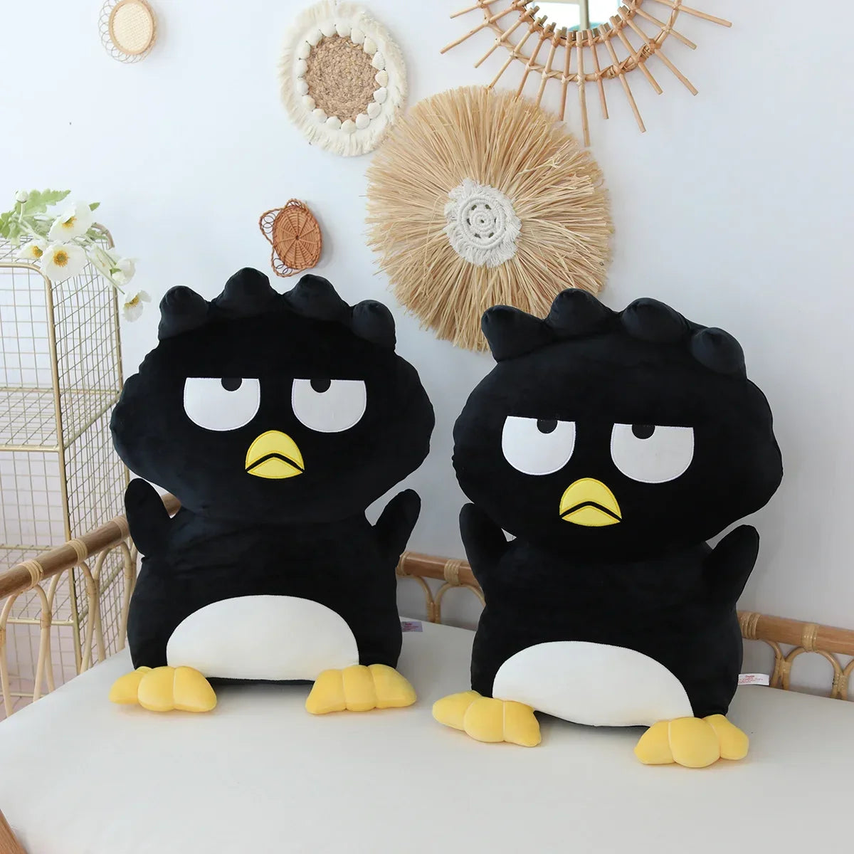 Two black plush toys with white faces and yellow feet on a white surface.