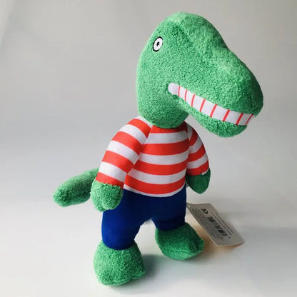 A green plush dinosaur toy wearing a red and white striped shirt and blue pants, standing against a light gray background with a small product tag attached.