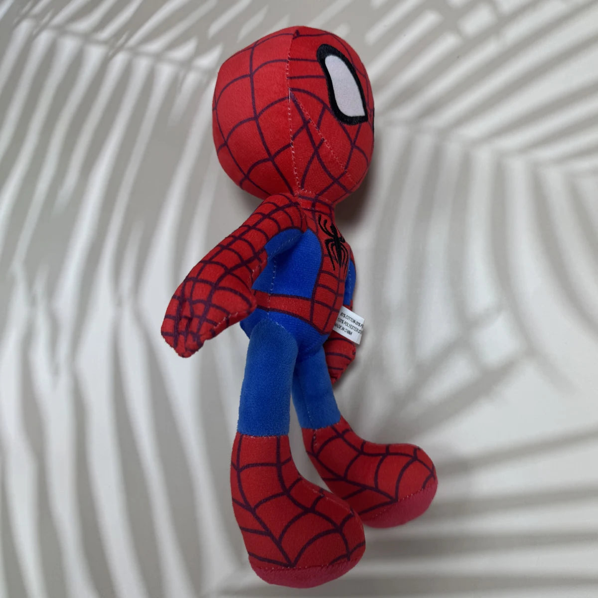 Plush toy Spider-Man on a textured white background