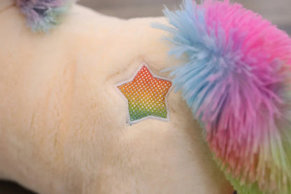 Toy with rainbow star patch and colorful pom-pom on a soft surface